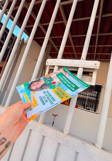 Mão segurando materiais eleitorais próximos à entrada de uma residência