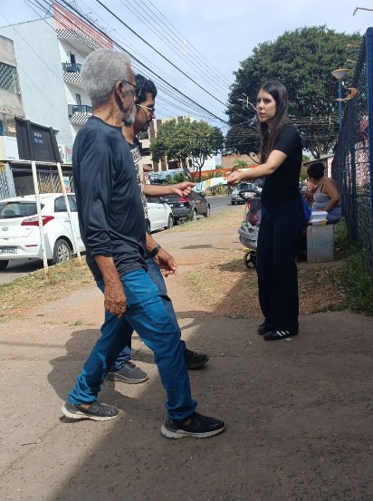 Agente de campo entregando material impresso a um pedestre em área urbana